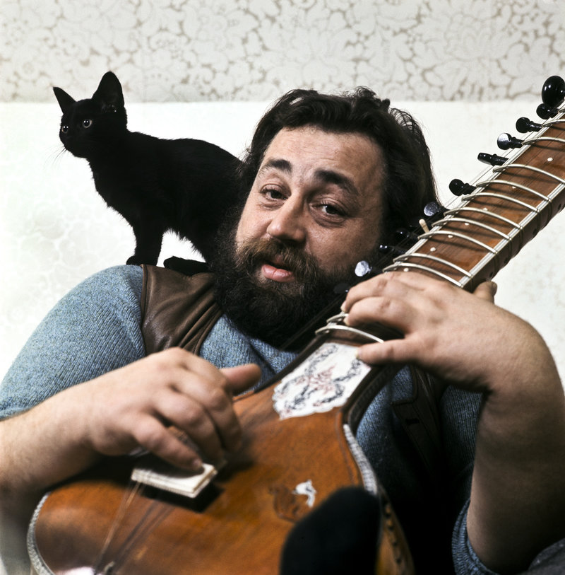 Trubaduren Cornelis Vreeswijk (1937-1987) med en sitar i famnen och sin svarta kattunge på axeln i hemmet. Arkivbild.