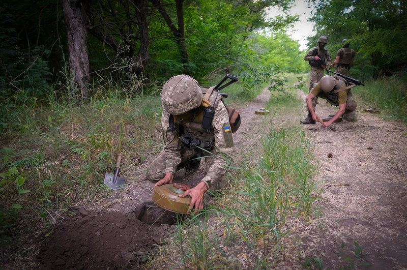 Ukrainska soldater lägger ut fordonsminor på en skogsväg någonstans i Donetsk.