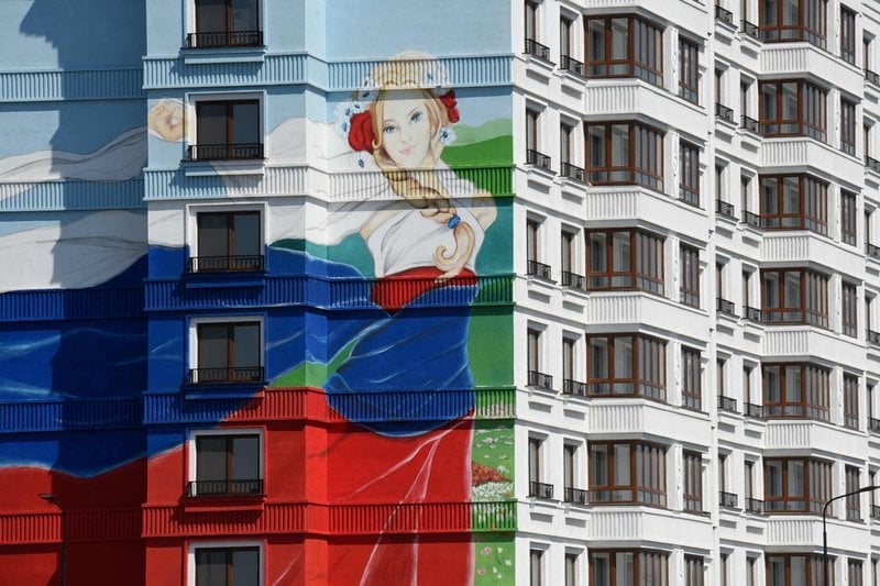 Ett nybyggt bostadshus i Mariupol har fått en väggmålning med en kvinna klädd i den ryska flaggans färger.