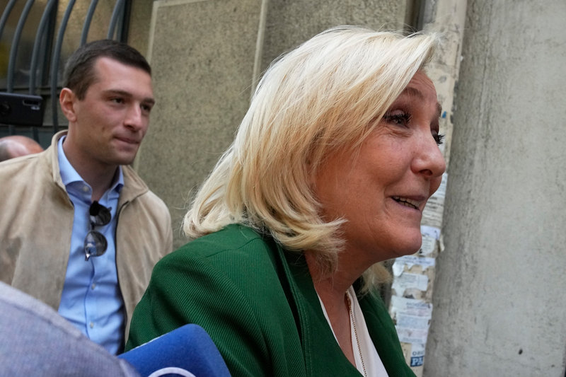 Nationalistledaren Marine Le Pen, följd av kronprinsen tillika tillförordnade partiledaren Jordan Bardella, vid partihögkvarteret i Paris i måndags.