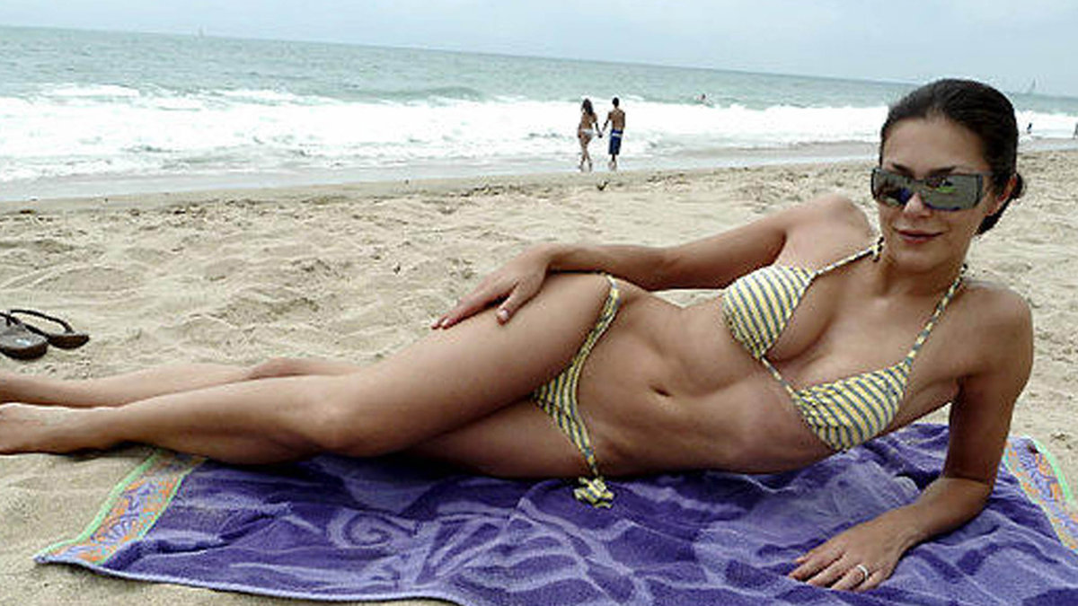 Modellen Adrienne Curry chillar på stranden. 