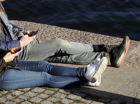 Människor sitter med mobiler i vårvädret. Människor sitter med mobiler i vårvädret.