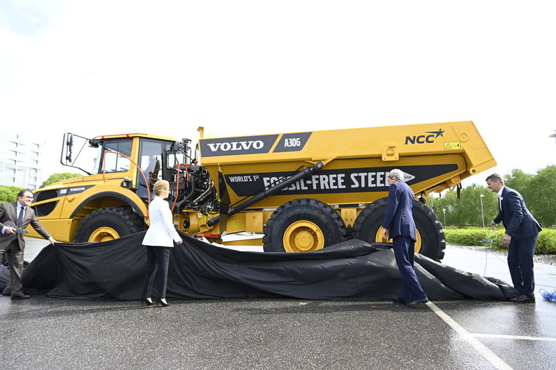 Volvos koncernchef Martin Lundstedt (till höger), USA:s klimatsändebud John Kerry (i mitten) och klimat- och miljöminister Annika Strandhäll avtäcker en anläggningsmaskin.