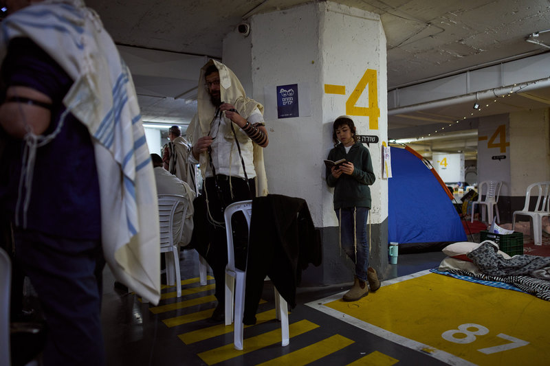 Religiösa israeler ber i ett underjordiskt garage medan flyglarmet ljuder i Tel Aviv på tisdagen.