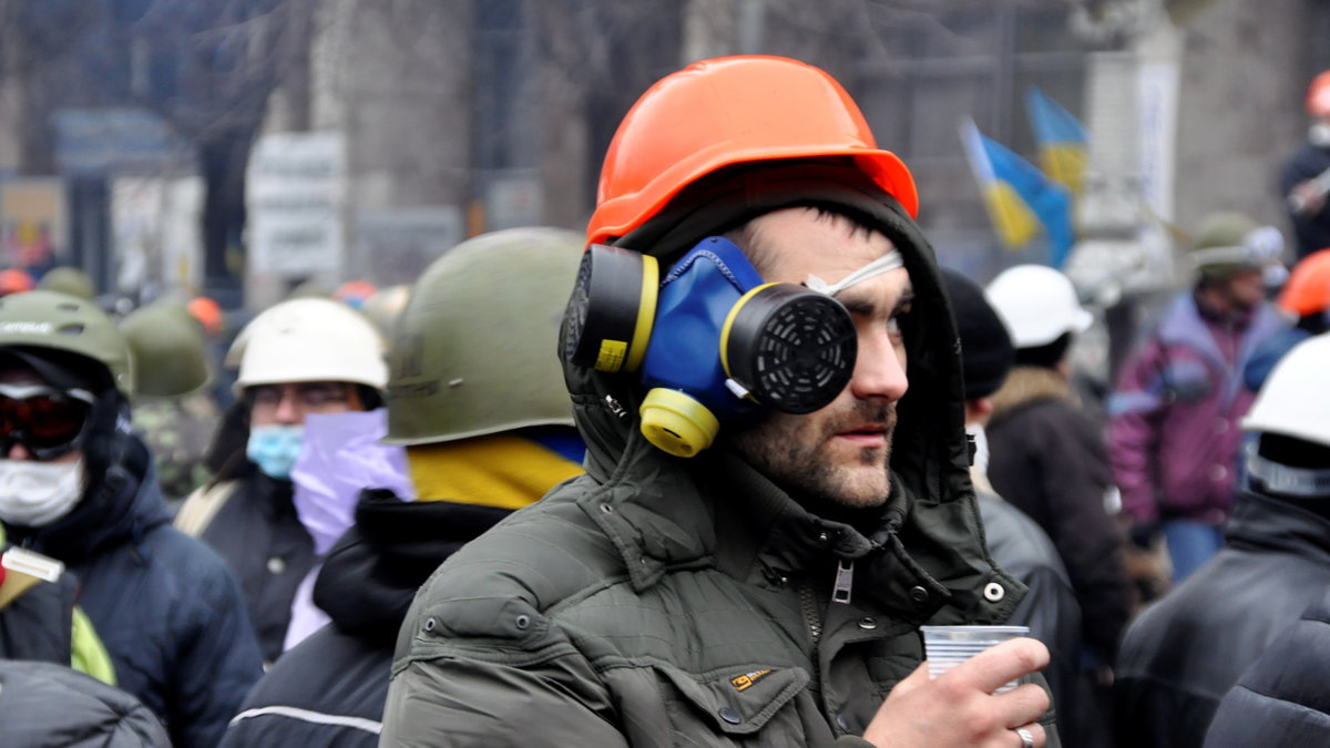 Man vätskar upp med gasmasken i beredskap på Självständighetstorget i Kiev.