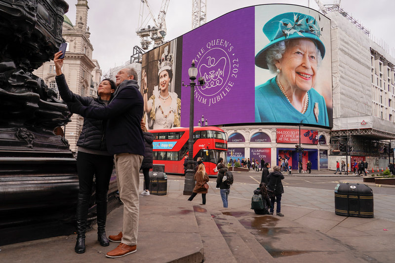 Ett par på Piccadilly Circus i centrala London tar en selfie med drottningfirandet som bakgrund.