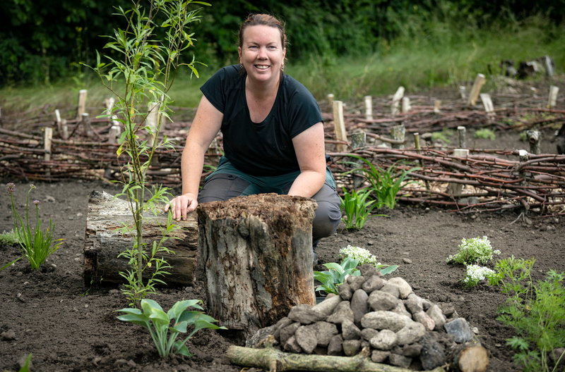 Caroline Stenkilsson, trädgårdsmästare, i sin plantering med stubbar.