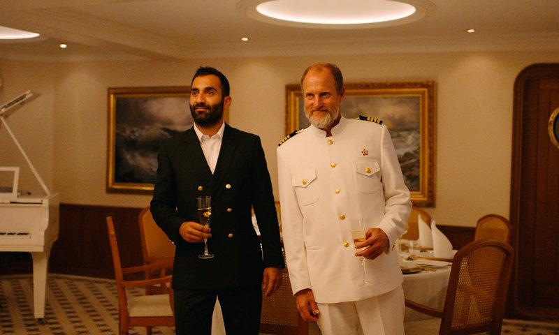 Arvin Kananian och Woody Harrelson strax innan kräkfesten brakar loss i 'Triangle of sadness'. Pressbild.