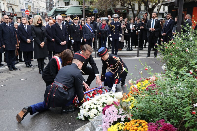 Frankrikes president lägger en minneskrans vid kafeet Le Bonne Biere café i Paris där flera personer dödades i terrordådet för tio år sedan.