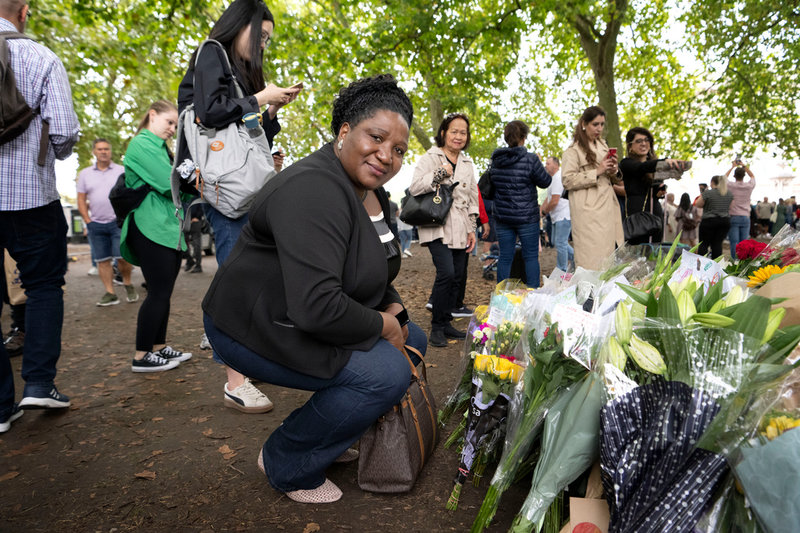 Anita Tweh lägger blommor vid ett träd i närheten av Buckingham Palace i London med anledning av drottning Elizabeths bortgång.