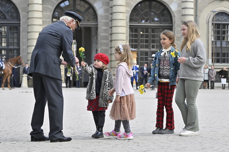 En grupp barn uppvaktar kungen med blommor.