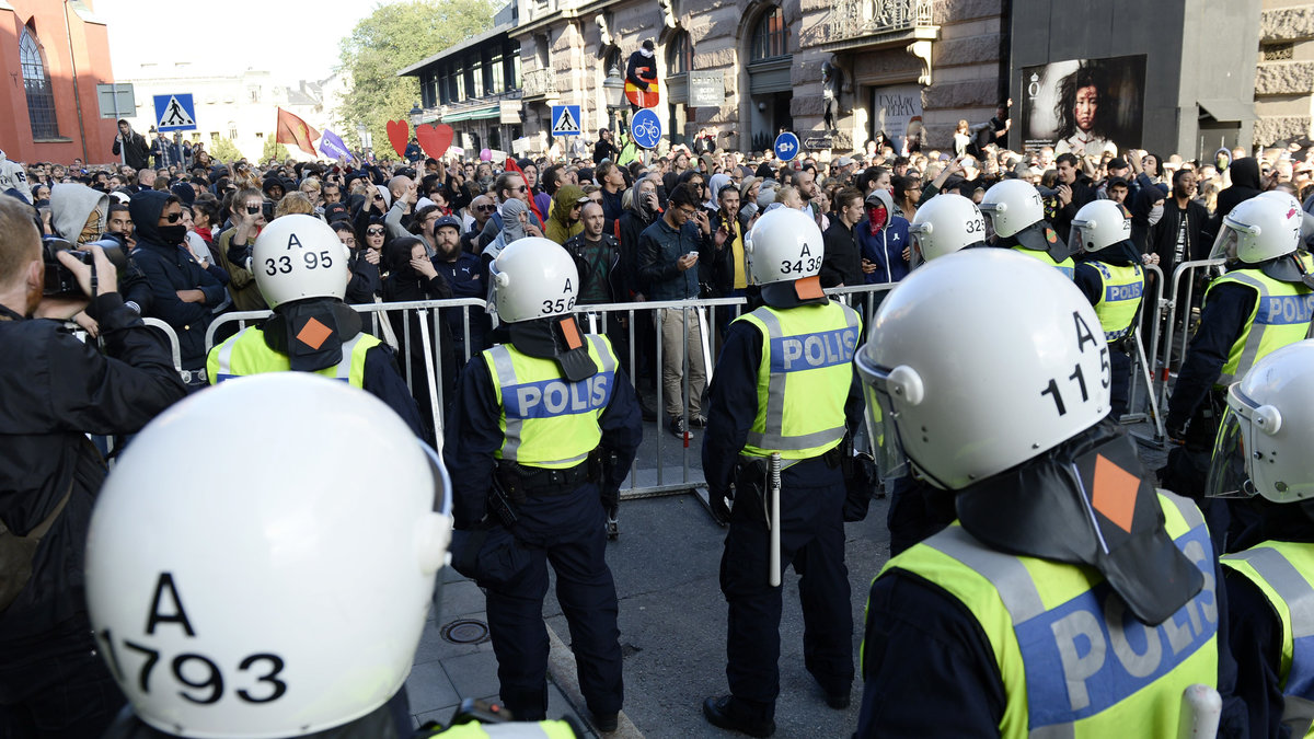 Polis och antinazistiska motdemonstranter, åtskilda av kravallstängsel.