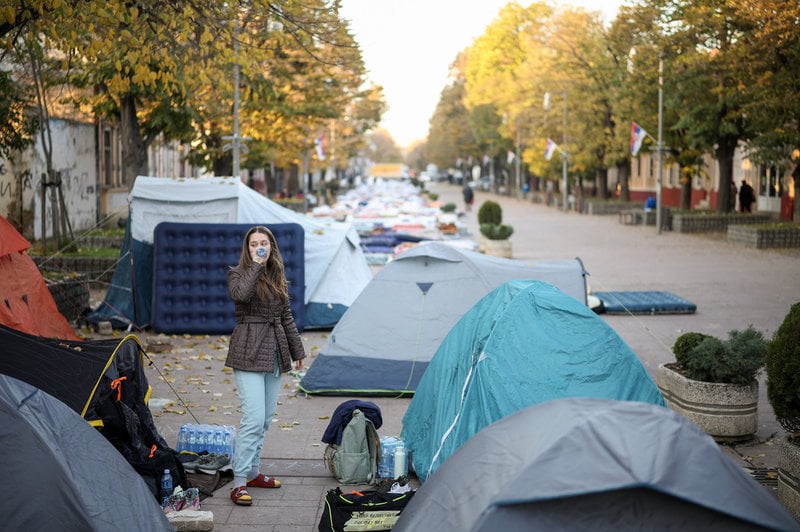 En student dricker vatten efter att ha övernattat i Indjija strax utanför Novi Sad. Demonstranter som marscherat och mobiliserat genom landet tog en paus där över natten till fredag.