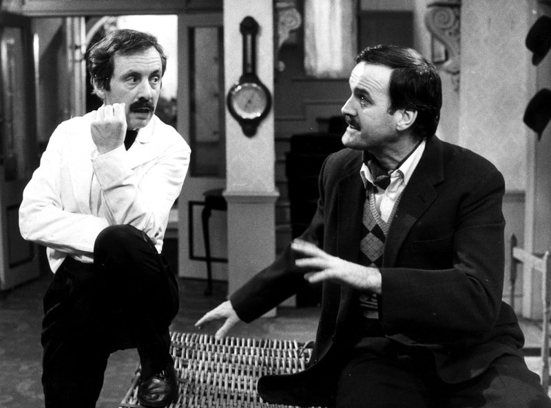 Andrew Sachs som Manuel och John Cleese som Basil Fawlty i komediserien 'Pang i Bygget'.