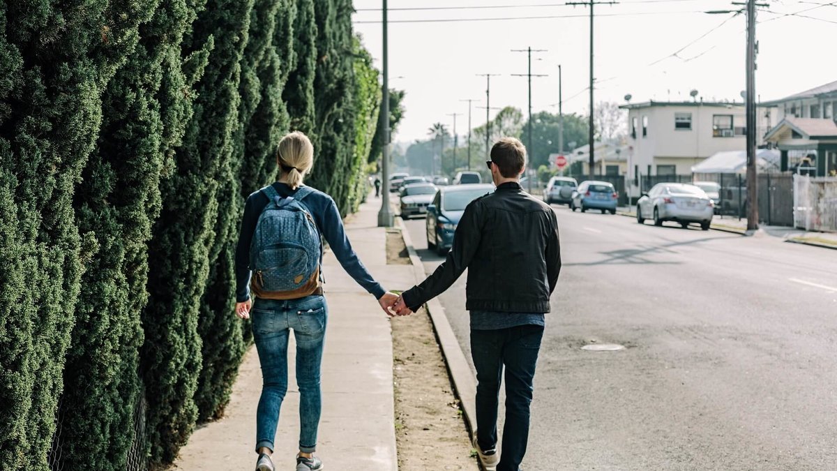 Par går längs en gata och håller hand med varandra