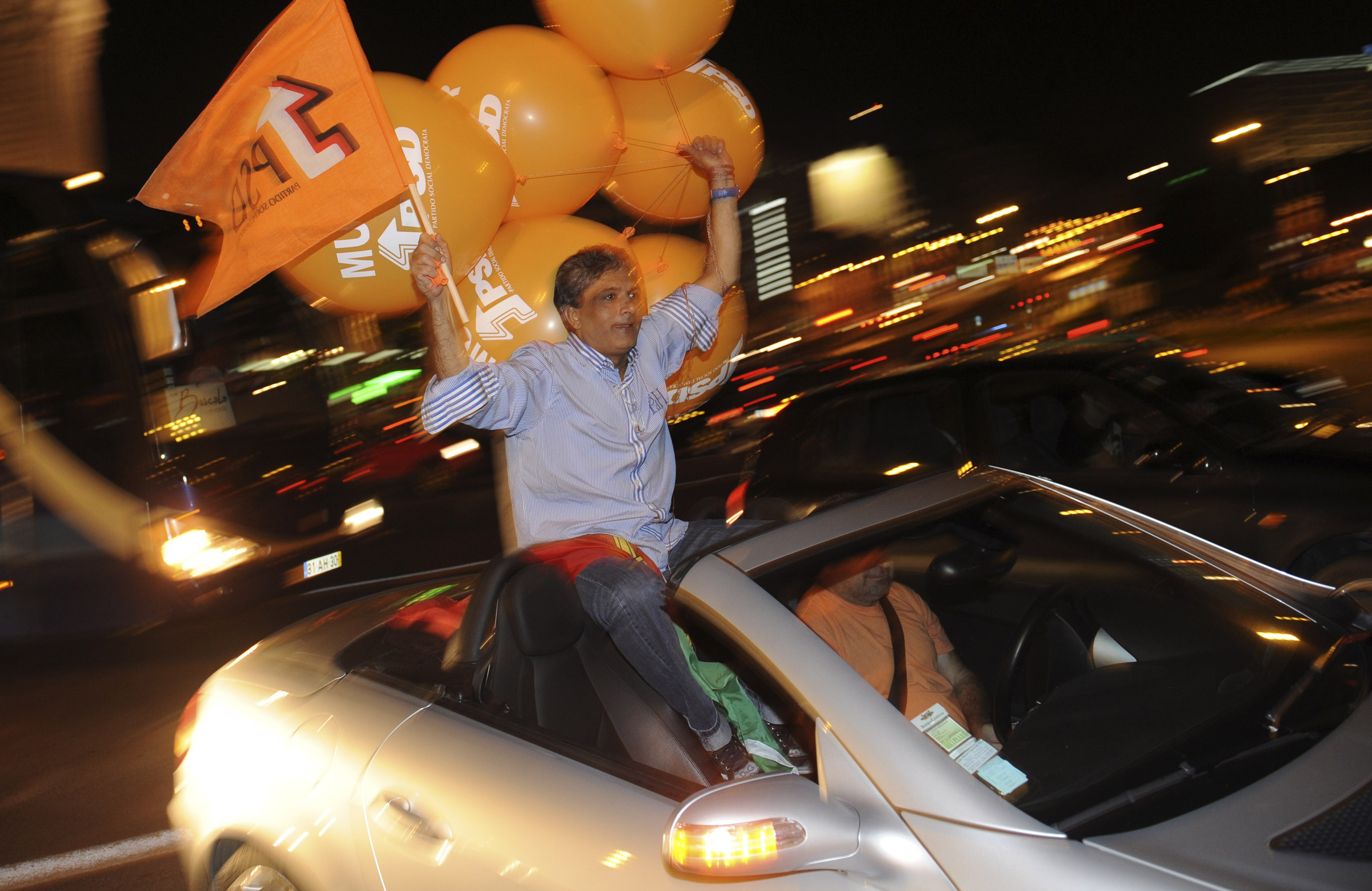 Portugisiska PSD har, precis som alliansen i Sverige, valt orange som sin färg. Här firar en anhängare på Lissabons gator.