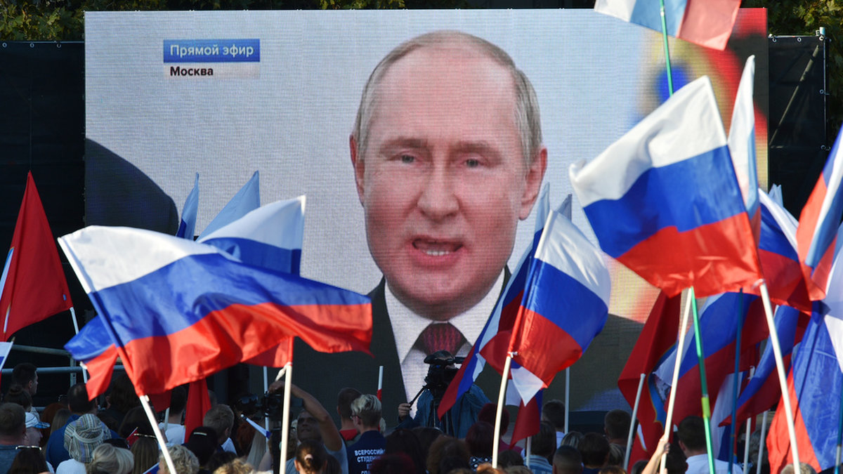 Människor ser på storbilds-tv president Vladimir Putin hålla tal inför annekteringen av fyra områden i Ukraina.