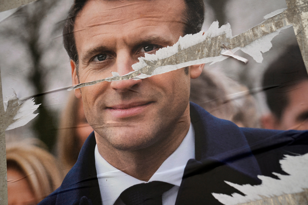 President Emmanuel Macron på en sönderriven valaffisch i Paris. Presidenten hoppas bli första franska ledare att bli omvald sedan Jacques Chirac 2002.