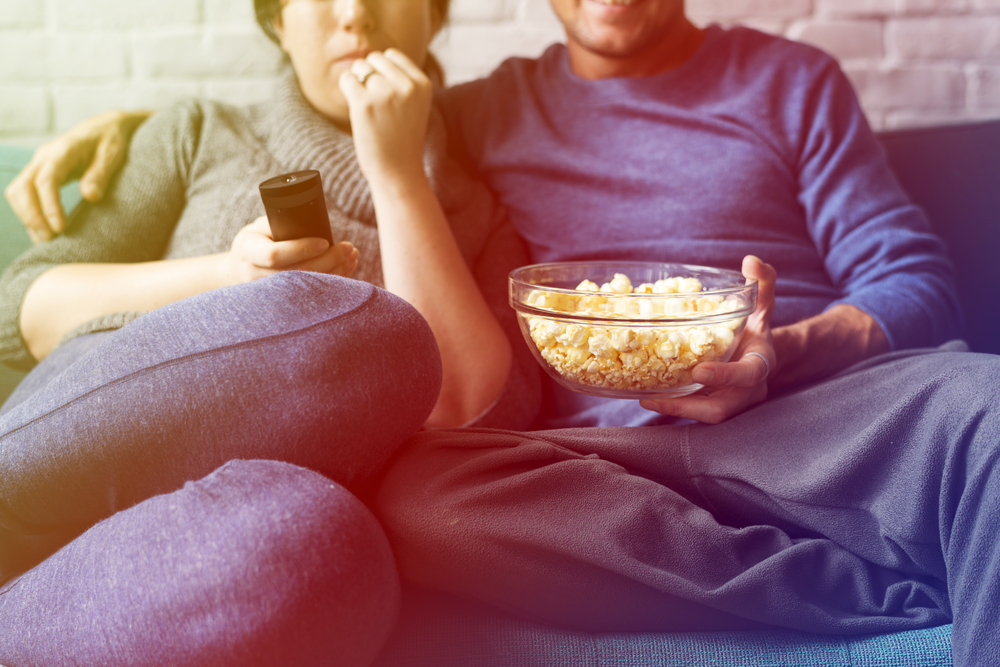 Ett par som äter popcorn och tittar på film. 