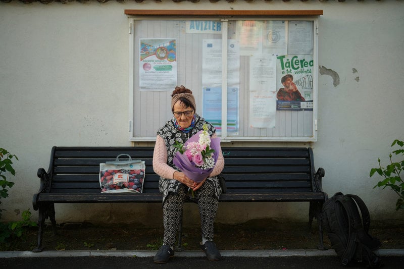 En kvinna sitter och väntar utanför en vallokal på söndagen i Mogosoaia i Rumänien.