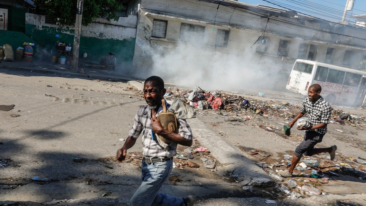 Män springer för att ta skydd från polisens tårgas i centrala Port-au-Prince den 2 april.