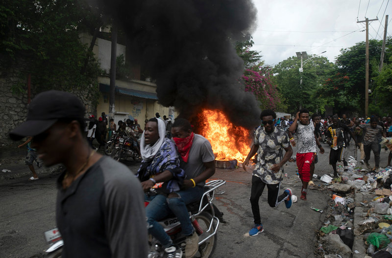 Människor springer förbi en brinnande barrikad under protesterna i Haitis huvudstad Port-au-Prince.