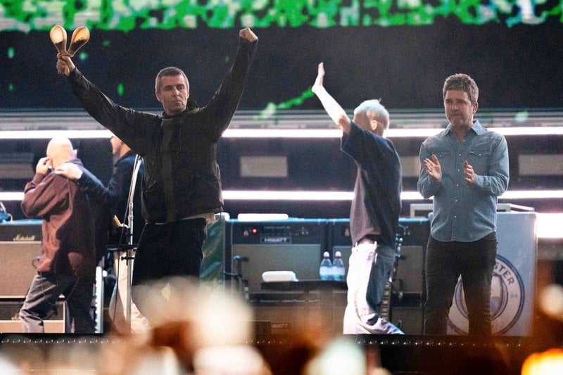 Liam och Noel Gallagher tar emot publikens jubel under turnépremiären i Cardiff i juli.