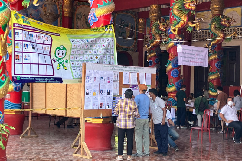 Väljare läser på om valkandidaterna innan de lägger sina röster vid en vallokal i Bangkok.
