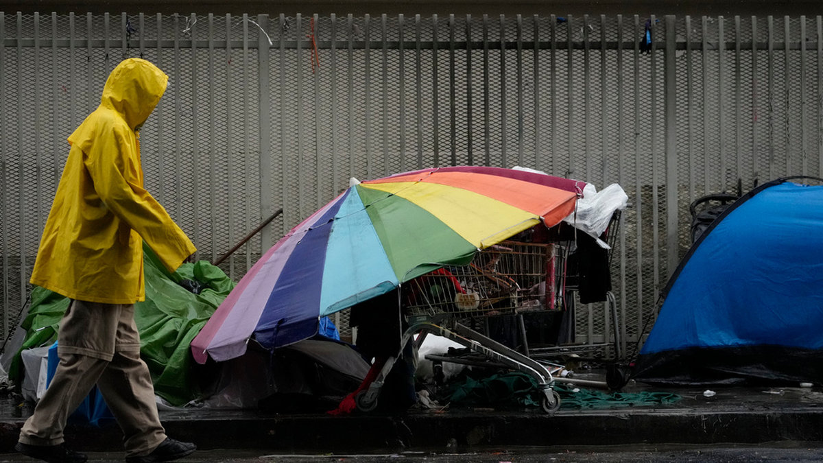En man promererar i det kraftiga regnovädret i Los Angeles-området Skid Row, där ett stort antal hemlösa håller till.