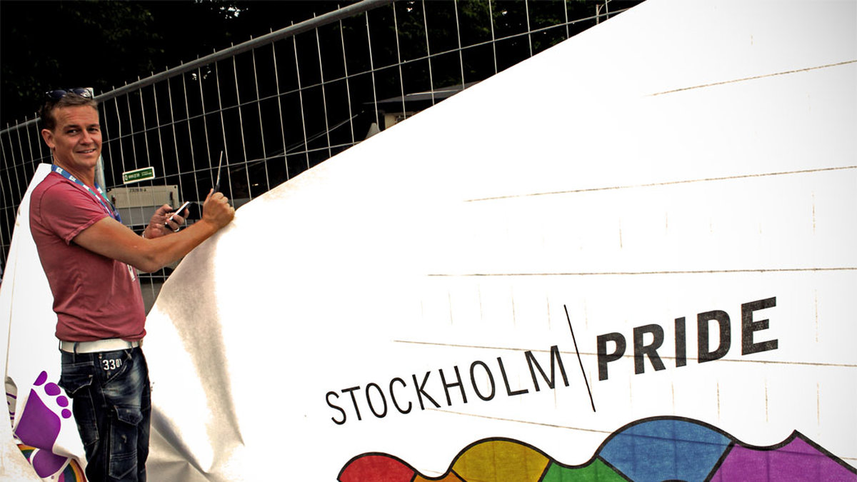 Mickael Kröger sätter upp en Pride-flagga i Pride Park.