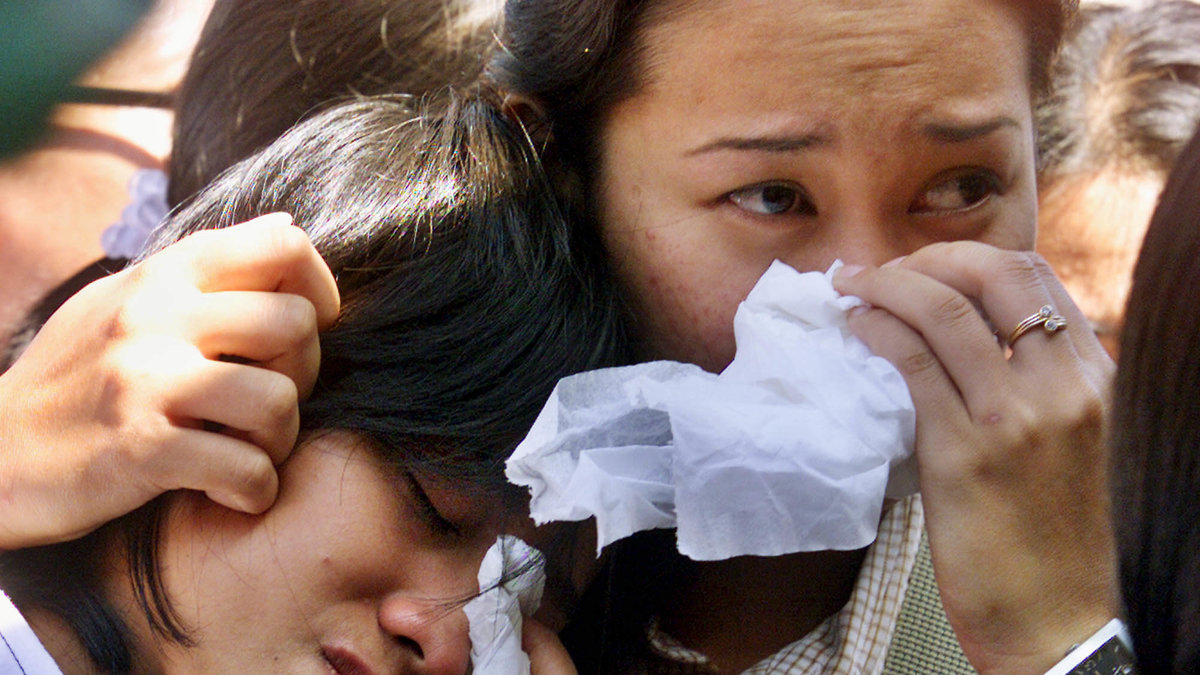 Två indonesiska kvinnor gråter när de identifierar en väns kropp efter explosionerna i Kuta.