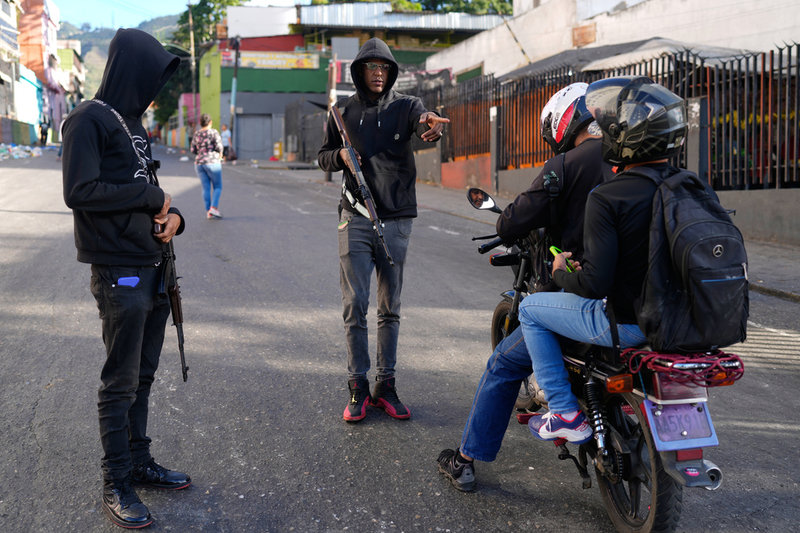Regimtrogna personer med vapen stoppar två personer på en motorcykel i Caracas på söndagen.