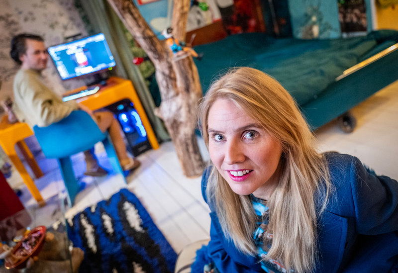 Författaren Amanda Romare fotograferad i fåtöljen hon brukar sitta i då hon skriver sina böcker hemma i lägenheten i Malmö. I bakgrunden pojkvännen Jens. 