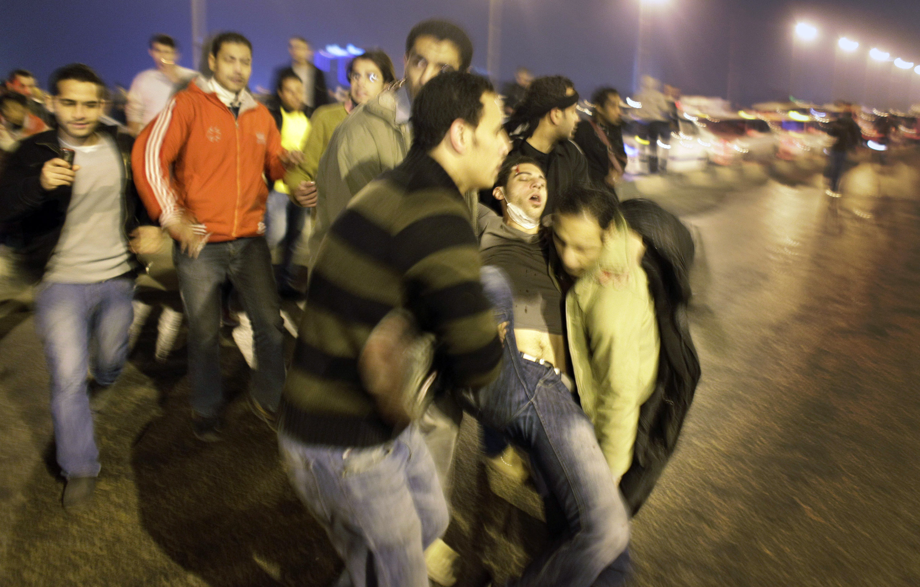 En sårad demonstrant bärs bort av sina kamrater under nattens protester i Kairo.