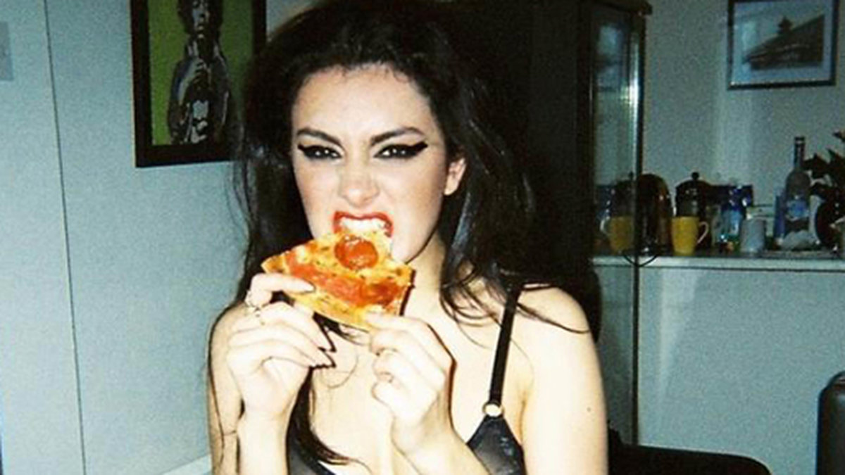 Charli XCX mumsar i sig pizza.