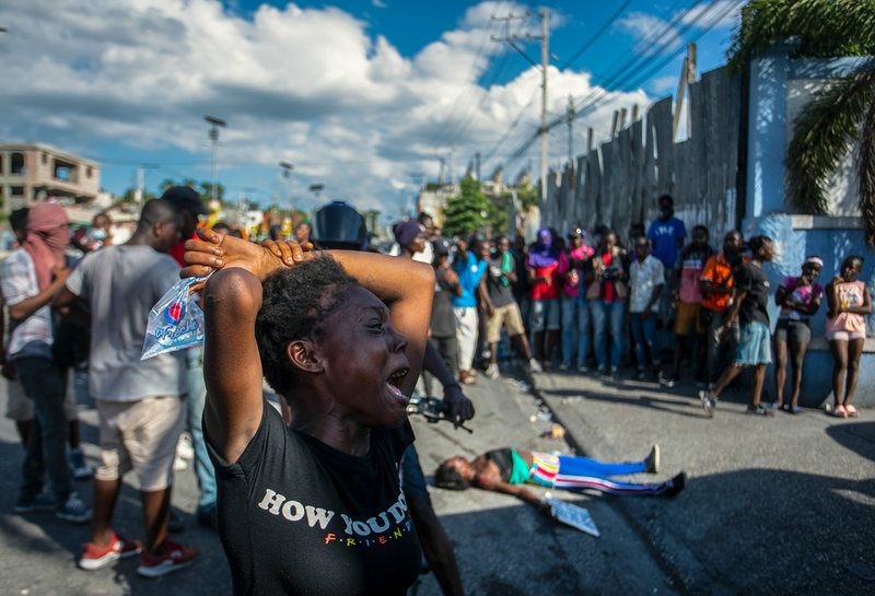 En kvinna gråter förtvivlat vid en protest i Port-au-Prince den 10 oktober. I bakgrunden står människor och betraktar en kvinna som skjutits till döds av polisen. Arkivbild.