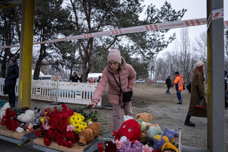 En kvinna lämnar en blombukett vid en busshållplats för att hedra de som dödades i den ryska attacken mot Dnipro.