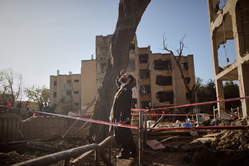 En man betraktar bostadshus som skadats i en iransk attack mot Arad i södra Israel.