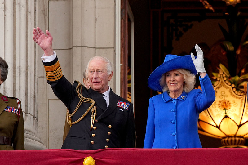 Kung Charles III och drottning Camilla vinkar till folket från en balkong på Buckingham Palace – samma balkong som dåvarande kung George VI firade krigsslutet på 1945.