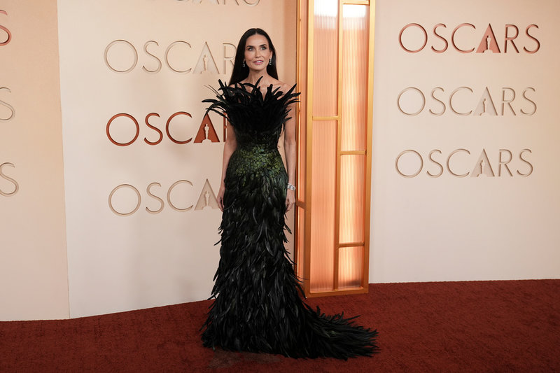 Demi Moore i en grönsvart kreation med fjädrar.