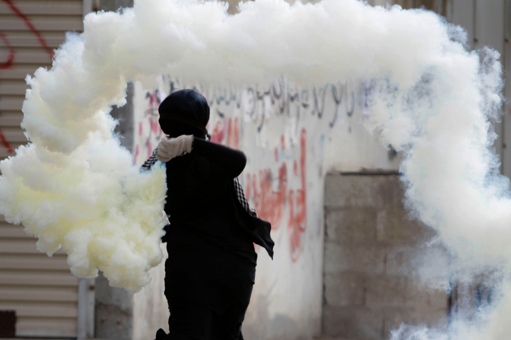 En demonstrant kastar tillbaka en tårgaspatron mot säkerhetsstyrkorna under oroligheter i Bahrain.