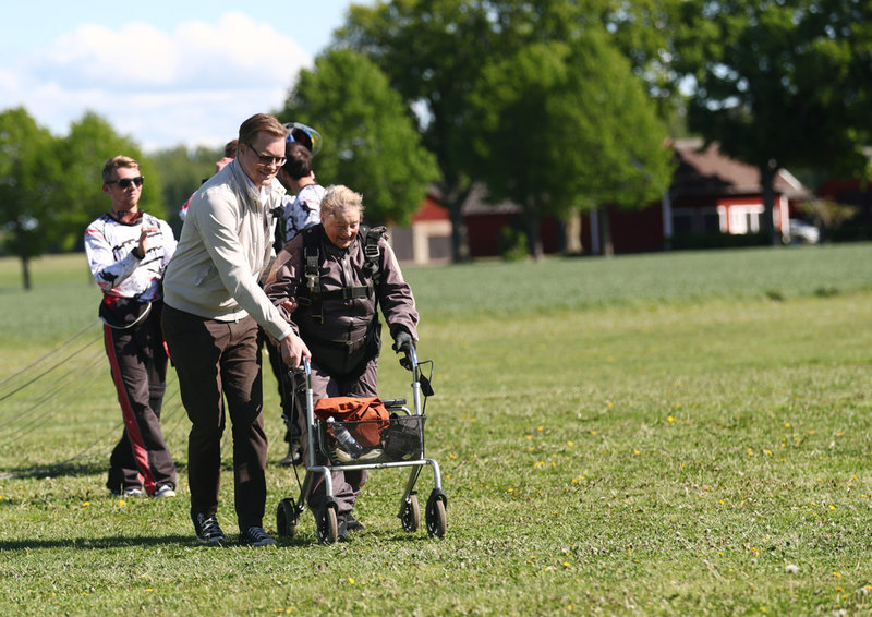 Rut Larsson, 103, får hjälp av sonen Per att ta sig av landningsbanan i Motala efter det lyckade hoppet.
