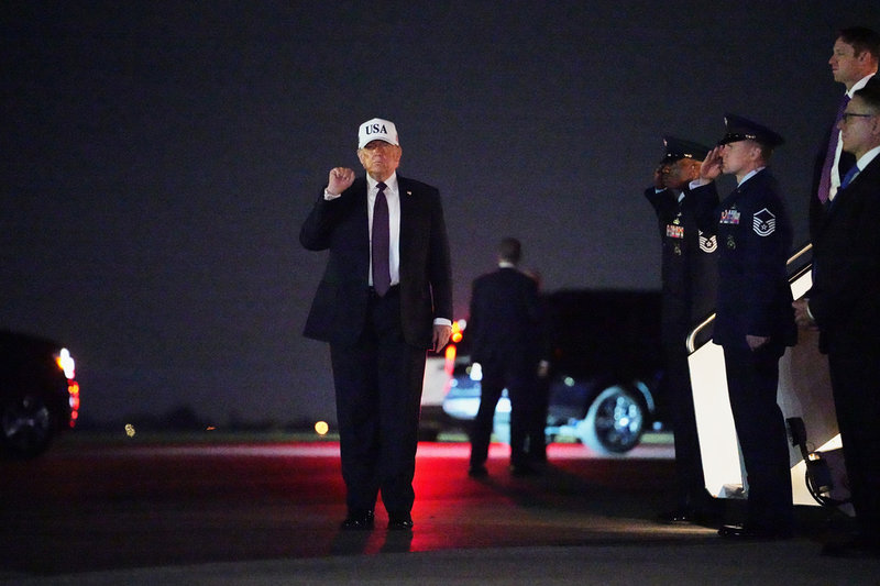 USA:s president Donald Trump höjer näven i luften efter att ha landat i Florida på fredagskvällen.