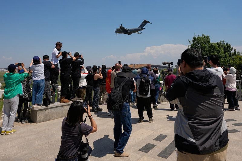Åskådare fotograferar ett amerikanskt militärt transportflygplan som anlände till Peking på måndagen inför Donald Trumps besök.