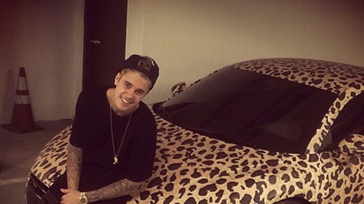 Justin Bieber poserar med sin riviga bil.
