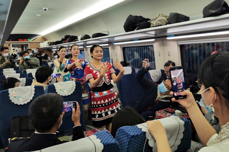 Kvinnor i folkdräkt uppträder på den kinesiska sidan gränsen för att fira trafikstarten mellan Kunming och Vientiane.