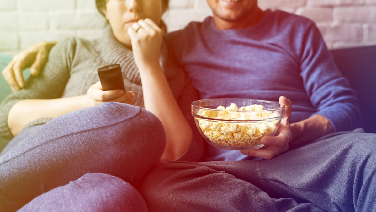 Ett par som äter popcorn och tittar på film. 