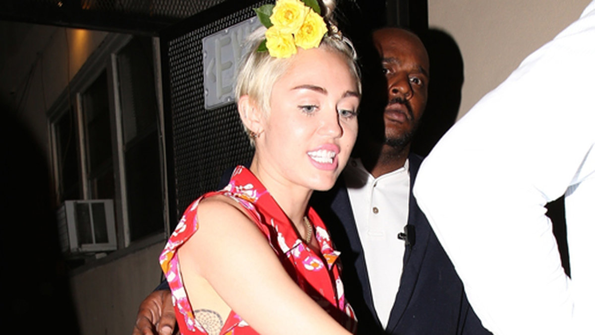 Miley Cyrus har blommor i sitt hår. 