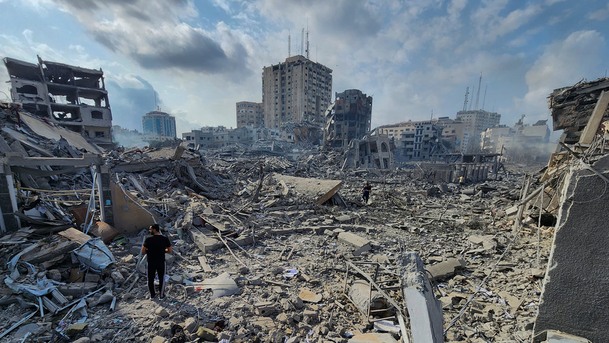 Palestinier går omkring i de rasmassor som återstår av byggnader som bombades sönder i staden Gaza den 10 oktober. Arkivbild.