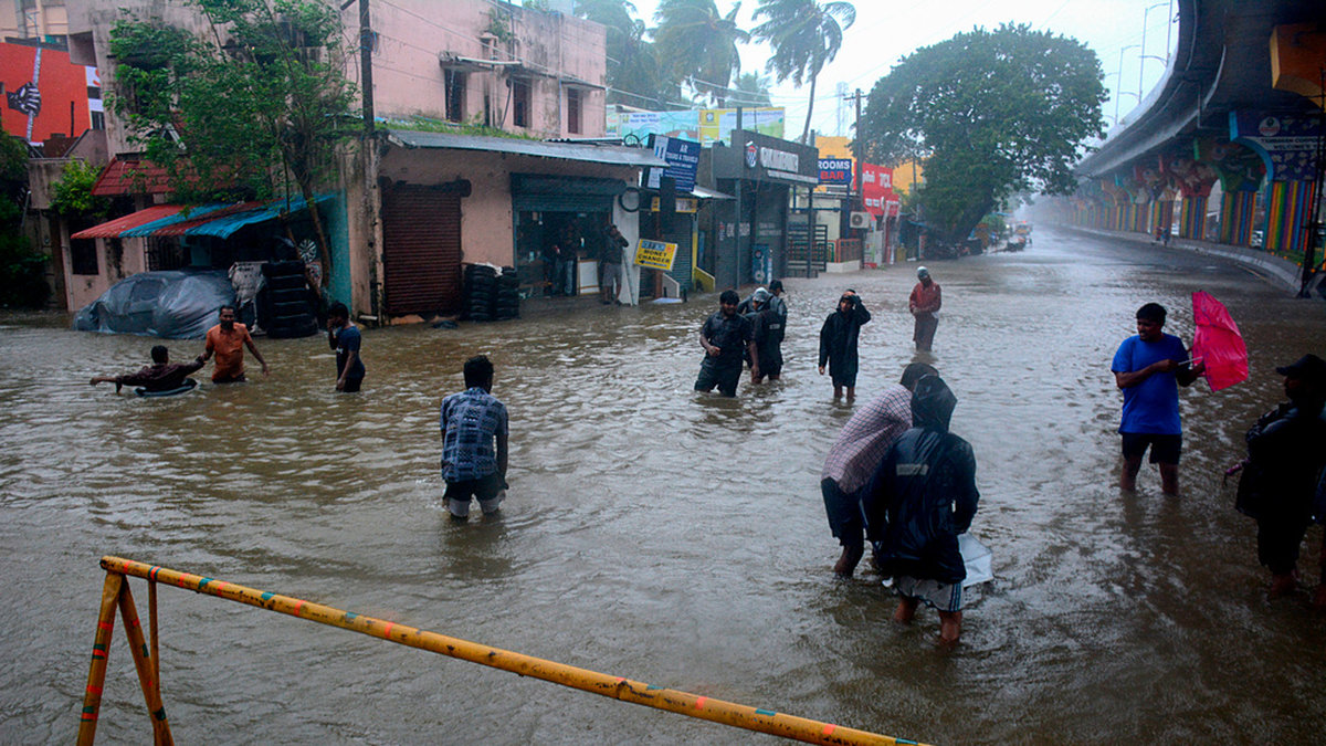 Människor vadar i högt vatten i Tamil Nadus delstatshuvudstad Chennai.